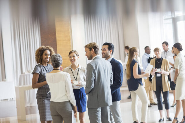 Group of business people standing in hall, smiling and talking together burger betrokkenheid
