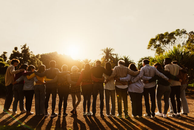 Back view of happy multigenerational people having fun in a public park during sunset time – Community and support concept Zijn wie je bent